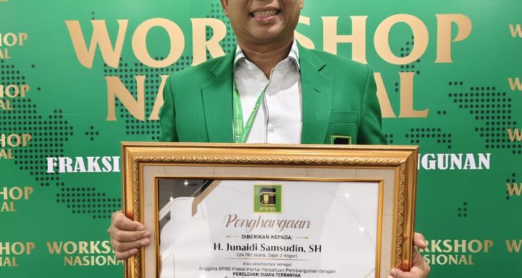 Junsam Saat Pegang Piagam Penghargaan