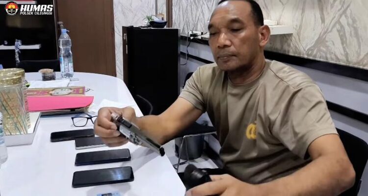Seorang petugas kepolisian dari Polsek Cileungsi duduk di meja sambil memeriksa barang bukti berupa senjata tajam dan beberapa unit ponsel yang diduga hasil kejahatan, di ruang pemeriksaan dengan latar belakang logo Humas Polsek Cileungsi.