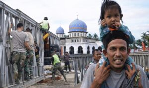Seorang warga yang menggendong anak Jembatan Teupin Mane yang menjadi akses penghubung dari Kabupaten Bireuen ke wilayah tengah atau pegunungan Aceh,Foto/Istimewa Seorang warga yang menggendong anak Jembatan Teupin Mane yang menjadi akses penghubung dari Kabupaten Bireuen ke wilayah tengah atau pegunungan Aceh,Foto/Istimewa